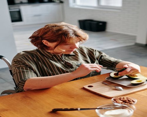 Variety of healthy foods like avocado, nuts, and fatty fish on a kitchen table